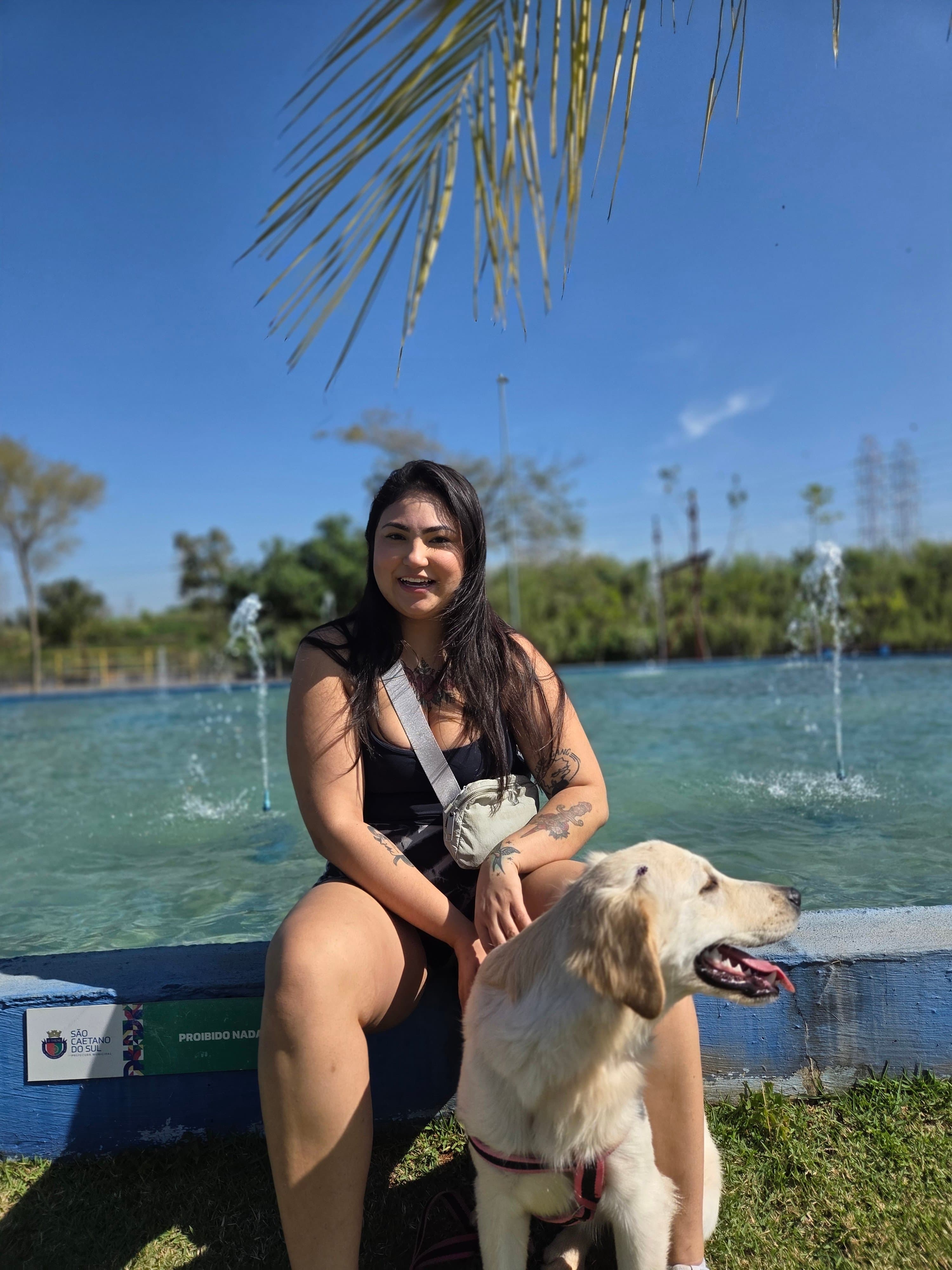 Larissa Freitas sorrindo ao ar livre ao lado de um cachorro